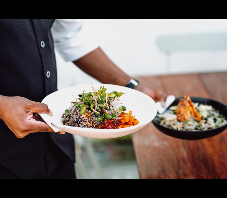 midsection-waiter-serving-two-dishes-wooden-table (1)